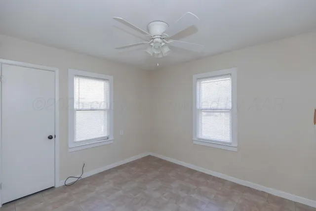 an empty room with a window and a fan