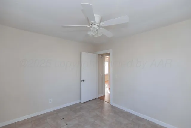 an empty room with a fan & a ceiling fan
