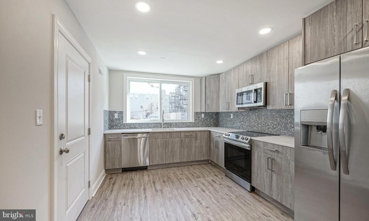 1702 North Gratz Street, Unit 1 Philadelphia, PA 19121 - Photo 1 of 12 a kitchen with stainless steel appliances granite countertop hardwood floor sink stove and refrigerator