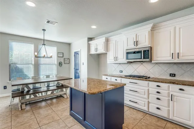 a large kitchen with kitchen island granite countertop a stove a sink and dishwasher wooden cabinets with granite countertops