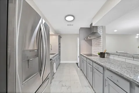 a bathroom with a granite countertop sink two mirror and a shower