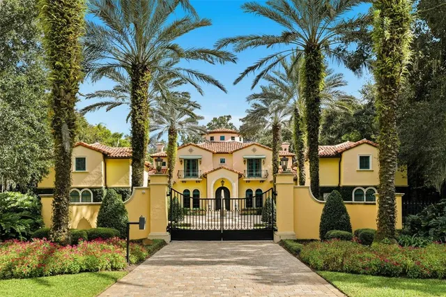 a view of a white house with a large tree and a yard in front of it