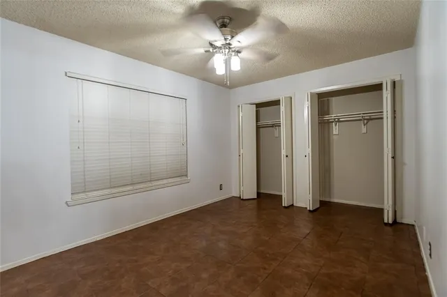 an empty room with closet and windows