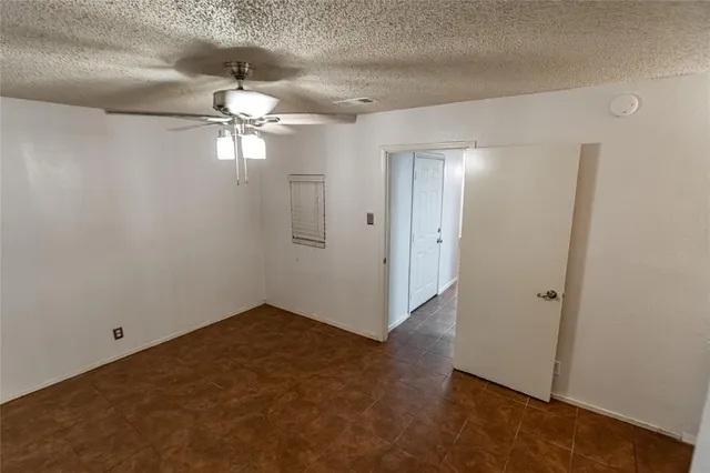 an empty room with chandelier fan and closet area