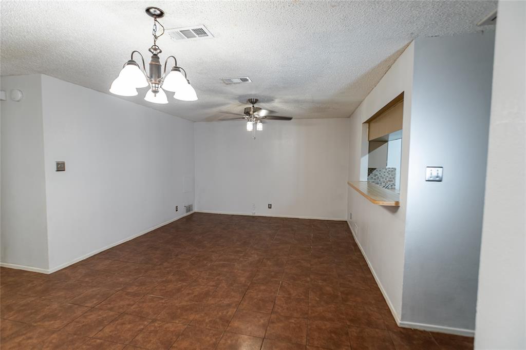 3327 Fallmeadow Street Denton, TX 76207 - Photo 5 of 31 en empty room with chandelier fan and kitchen view