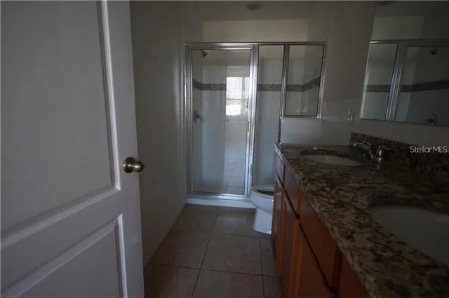 a bathroom with a granite countertop sink a toilet and shower