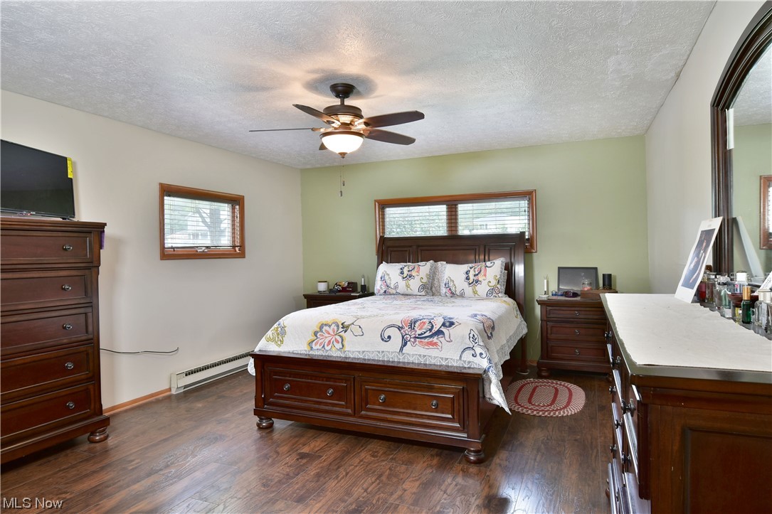 1711 Salt Springs Road Mineral Ridge, OH 44440 - Photo 22 of 35 Hardwood floored bedroom featuring a baseboard heating unit, a textured ceiling, and ceiling fan