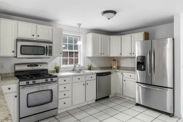 a kitchen with white cabinets stainless steel appliances and a window