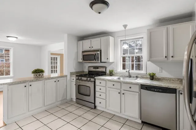 a kitchen with white cabinets appliances and a window