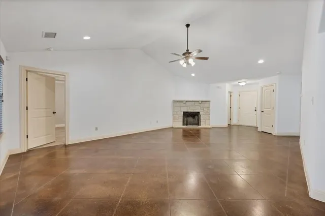 a view of an empty room with wooden floor fireplace and a window