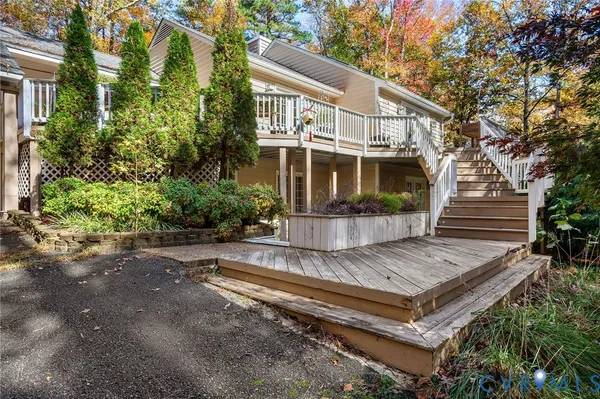 a view of a house with wooden deck and a yard with plants