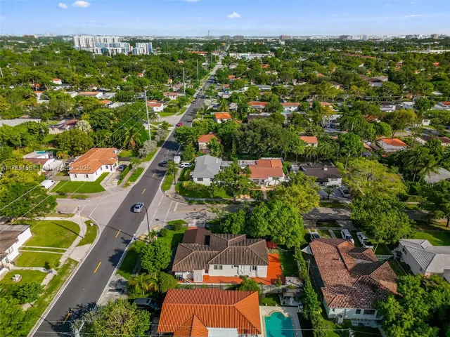 an aerial view of residential houses with outdoor space and trees