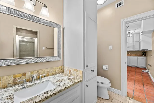 a bathroom with a granite countertop sink a toilet and a mirror