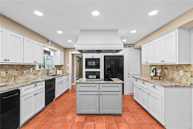 a large white kitchen with stainless steel appliances granite countertop a stove and a sink