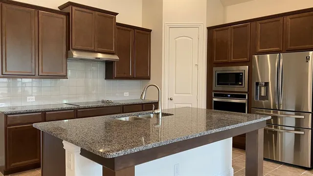 a kitchen with granite countertop a refrigerator and a sink