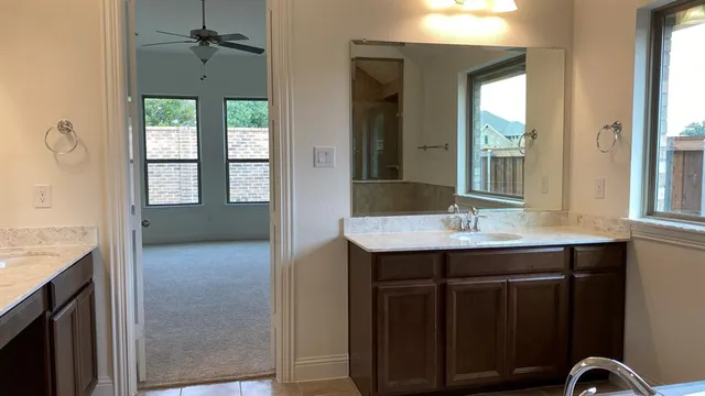 a bathroom with a granite countertop sink a toilet a mirror and next to a window