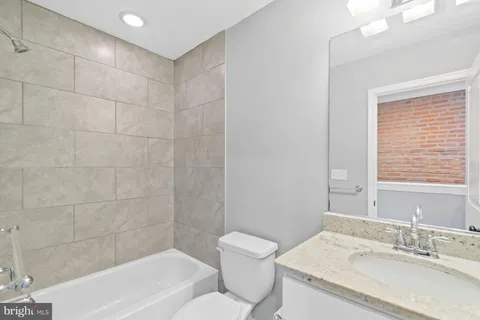 a bathroom with a granite countertop sink a toilet and bathtub
