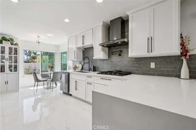 a kitchen with stainless steel appliances white cabinets a sink a stove a refrigerator and white cabinets