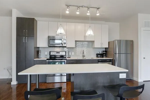 a kitchen with kitchen island a stove a refrigerator and a dining table with wooden floor