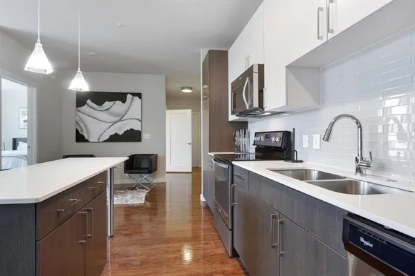 a kitchen with a sink dishwasher a stove and a microwave oven with white cabinets