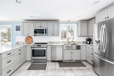 a kitchen with stainless steel appliances granite countertop a sink and dishwasher a refrigerator with white cabinets