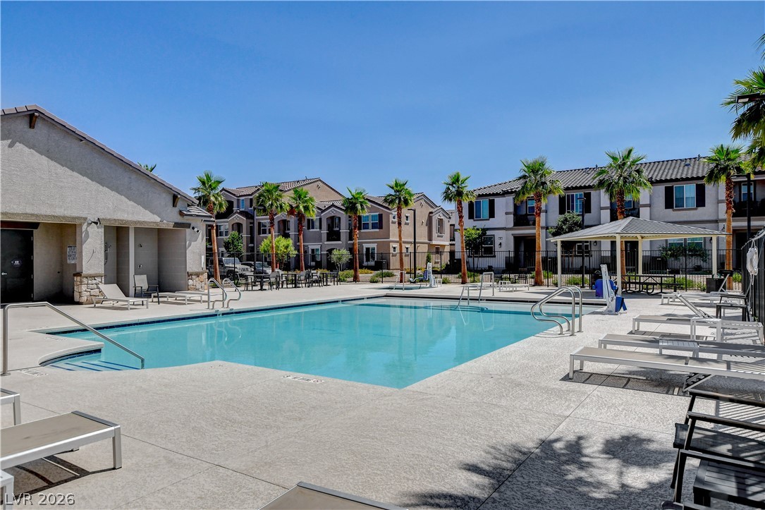 484 Filaree Place Henderson, NV 89015 - Photo 61 of 71 A refreshing pool awaits, surrounded by buildings and palm trees under a clear blue sky.