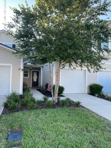 a view of a house with backyard and a tree