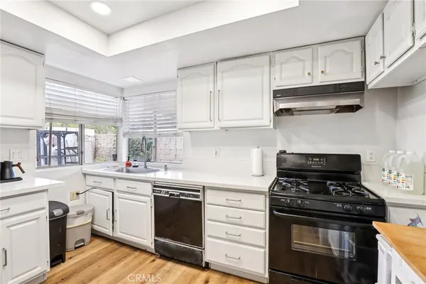 a kitchen with cabinets stainless steel appliances and wooden floor