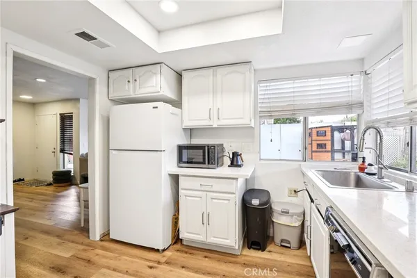 a kitchen with a refrigerator a stove top oven a sink and dishwasher with wooden floor