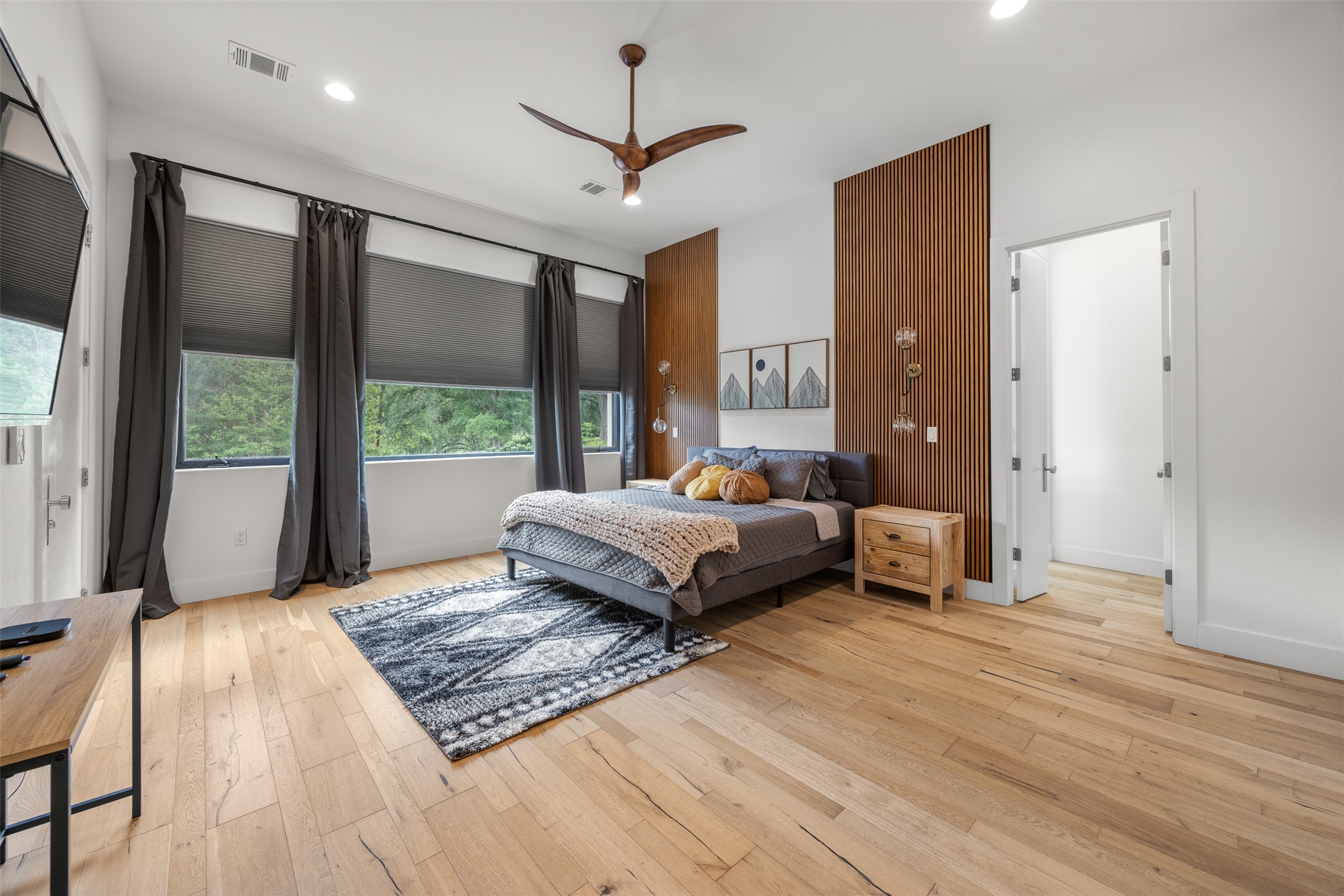 4103 Ridgelea Drive Austin, TX 78731 - Photo 15 of 26 An inviting bedroom with abundant natural light features warm hardwood flooring and modern wood slat accent walls.