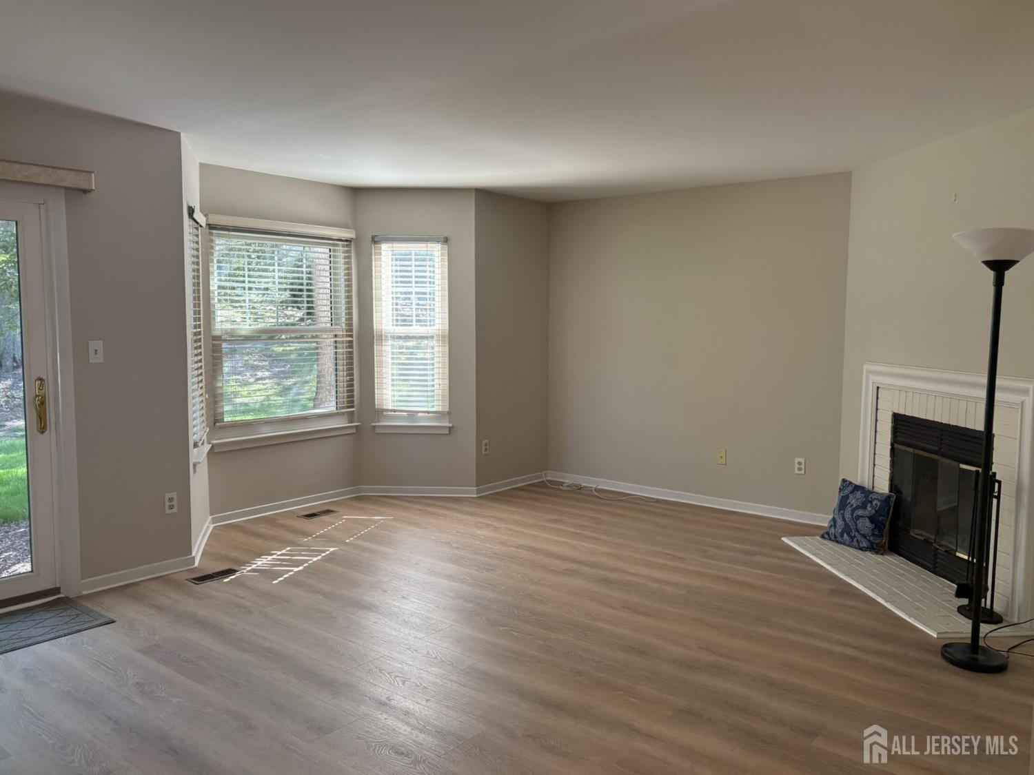 285 Greenfield Road Bridgewater, NJ 08807 - Photo 5 of 26 an empty room with wooden floor fireplace and windows
