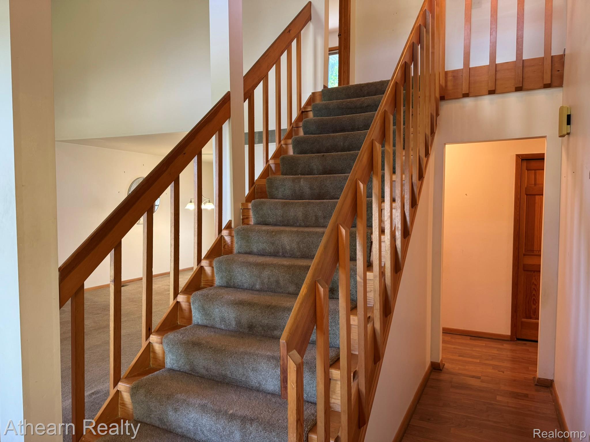 11449 Torrey Road Fenton, MI 48430 - Photo 19 of 30 Staircase with wood-finish handrails and spindles, carpeted treads, and wood-finish flooring in the foreground