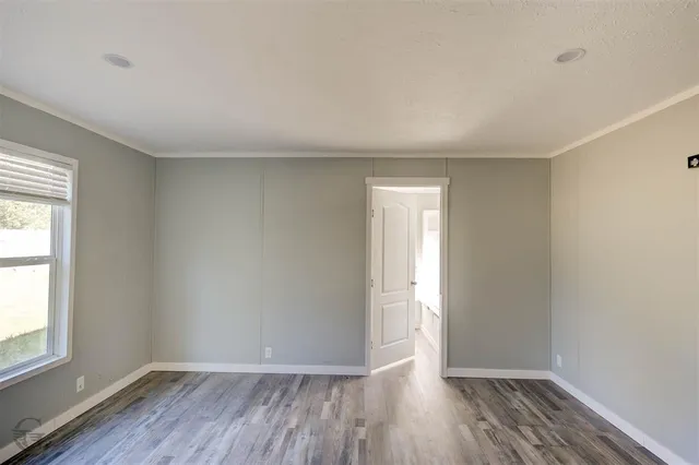 an empty room with wooden floor and window