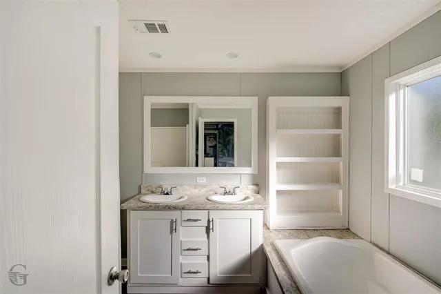 a bathroom with a sink vanity granite tub and a mirror