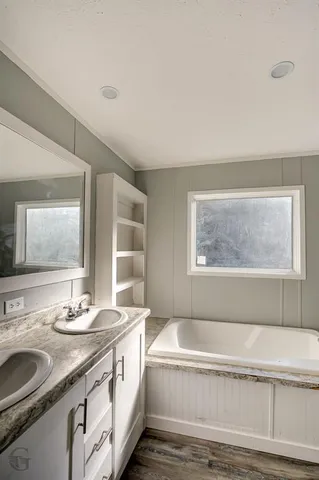 a bathroom with a granite countertop sink and a bathtub