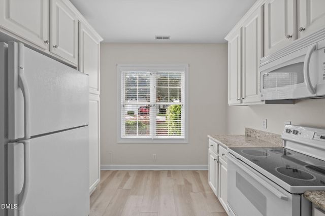 a kitchen with a refrigerator a stove a sink and a window with wooden floor