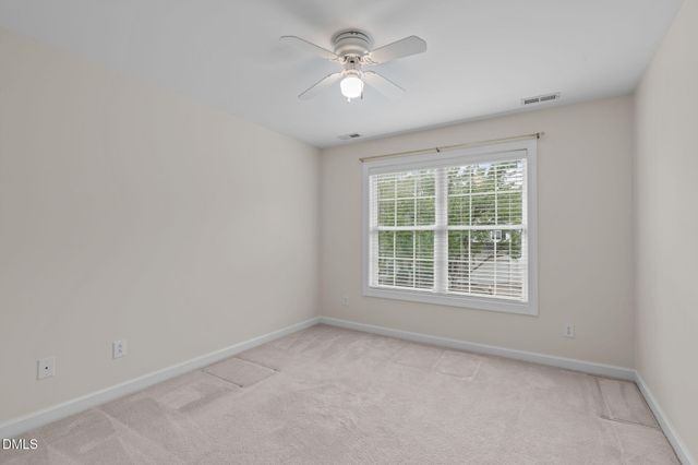 an empty room with a window and a fan