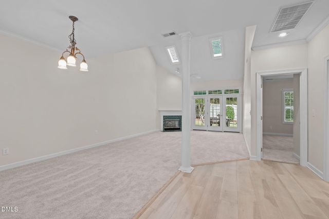 an empty room with chandelier fan and windows