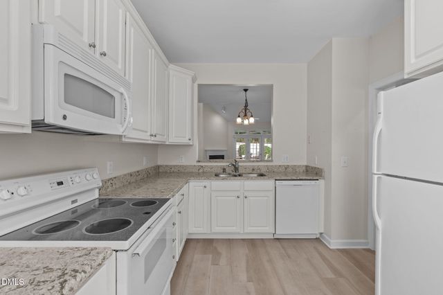 a kitchen with granite countertop white cabinets and white appliances