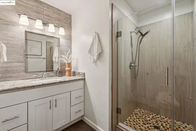 a bathroom with a granite countertop sink a mirror and shower