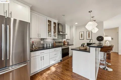 a kitchen with a refrigerator a stove cabinets and wooden floor