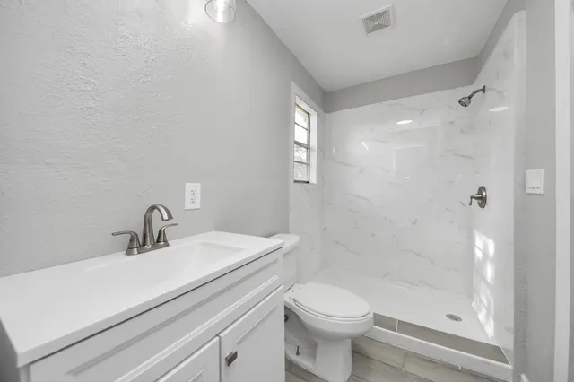 a bathroom with a sink a toilet and shower