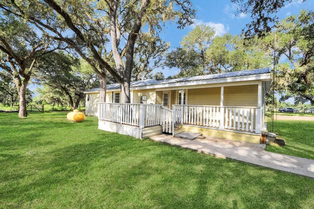 a backyard of a house with wooden fence and large trees