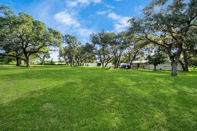 a view of grassy field with benches and trees all around