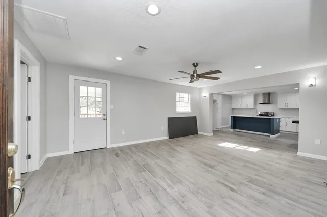 a view of empty room with wooden floor and kitchen view