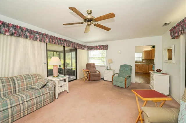 a living room with furniture ceiling fan and a large window