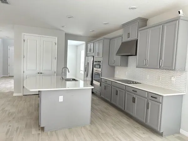 a large kitchen with stainless steel appliances granite countertop a lot of counter space and wooden floor