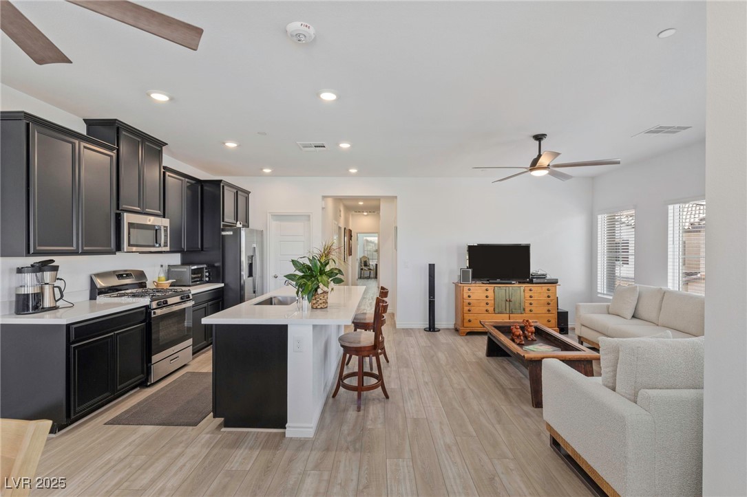 7230 North Decatur Boulevard, Unit 6 North Las Vegas, NV 89084 - Photo 26 of 27 Kitchen featuring a ceiling fan, appliances with stainless steel finishes, open floor plan, light countertops, and a breakfast bar