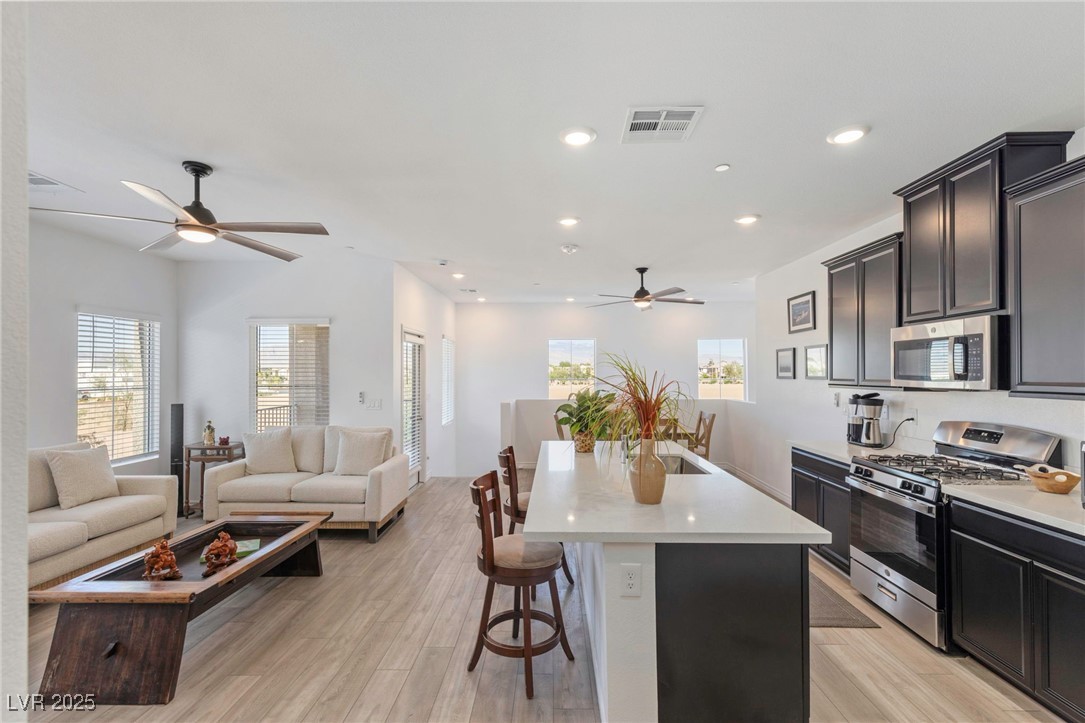 7230 North Decatur Boulevard, Unit 6 North Las Vegas, NV 89084 - Photo 27 of 27 Kitchen featuring ceiling fan, open floor plan, appliances with stainless steel finishes, an island with sink, and a breakfast bar