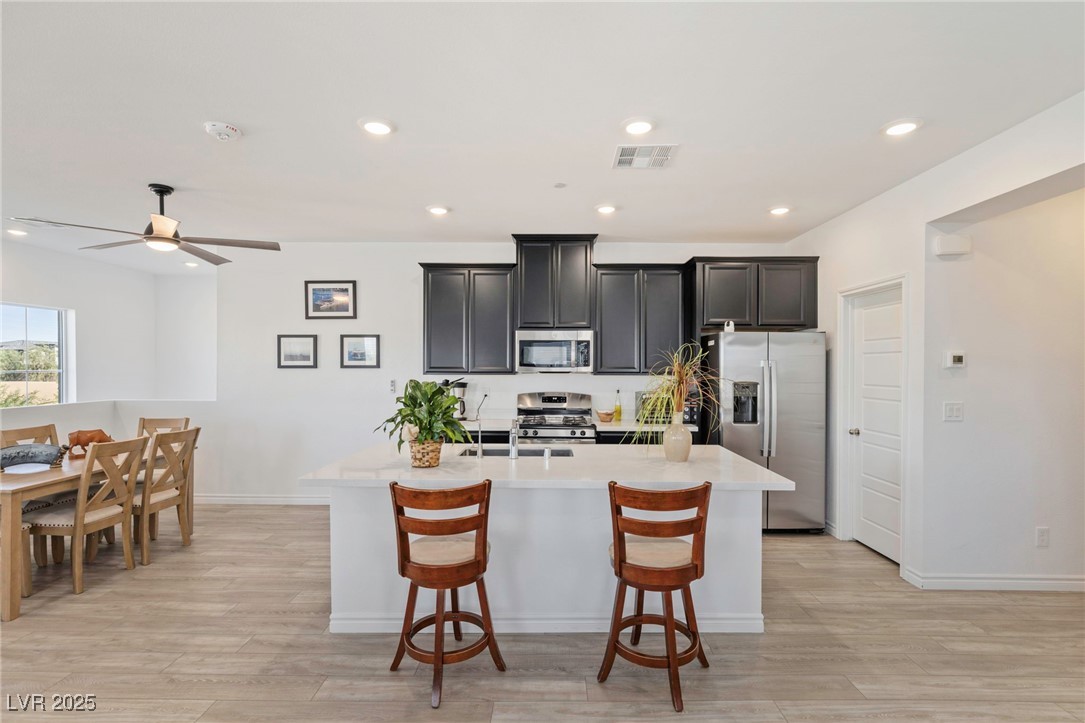 7230 North Decatur Boulevard, Unit 6 North Las Vegas, NV 89084 - Photo 6 of 27 Kitchen with stainless steel appliances, a center island with sink, light countertops, recessed lighting, and a kitchen bar